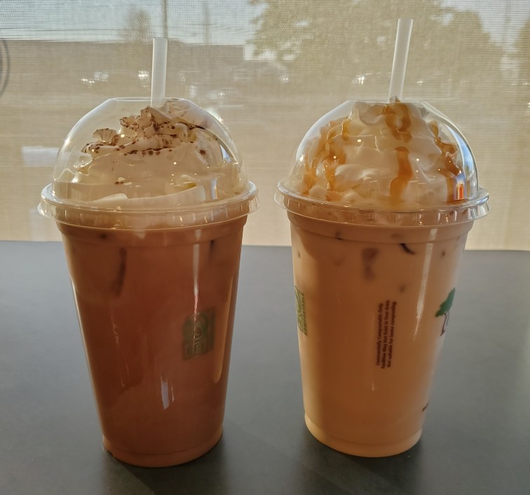 two iced coffees on a counter in front of a window